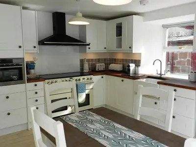 a kitchen with white cabinets and a stove top oven at Craigard Cottage in Corrie