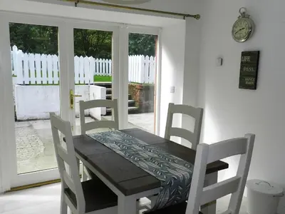 a wooden table and chairs in a room with a door at Craigard Cottage in Corrie