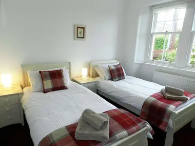 two twin beds in a room with two windows at Craegard House in Corrie