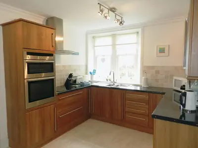 a kitchen with wooden cabinets and a sink and a window at Craegard House in Corrie