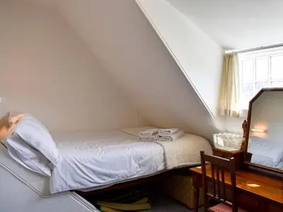 a small bedroom with a bed and a mirror at Hamilton Terrace in Lamlash