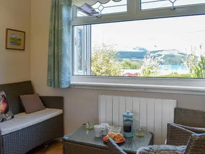 a living room with a table and a window at Fellview in Brodick