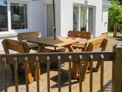a wooden table and chairs on a deck at Glen Rosa Lodge in Brodick