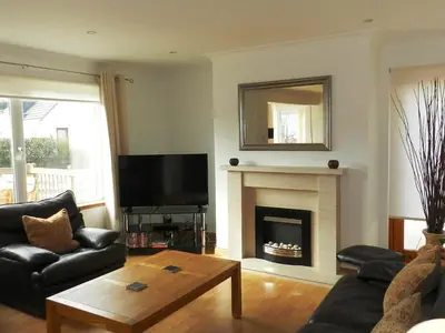 a living room with a television and a fireplace at Glen Rosa Lodge in Brodick