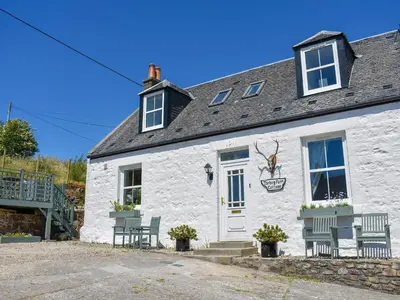 a white building with two chairs and a door at Torbeg Farm Cottage in Torbeg