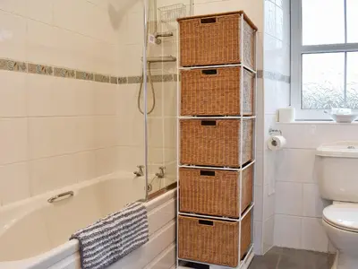 a bathroom with wicker baskets on the shower door at Torbeg Farm Cottage in Torbeg