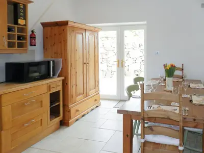 a kitchen with a wooden cabinet and a table with a tv at Torbeg Farm Cottage in Torbeg