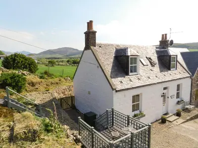 a white house with a staircase leading up to it at Torbeg Farm Cottage in Torbeg