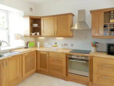 a kitchen with wooden cabinets and a sink at Torbeg Farm Cottage in Torbeg