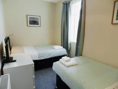 a room with two beds and a desk and a sink at Sunnyside Cottage in Lamlash