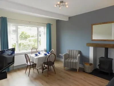 a dining room with a table and chairs and a fireplace at Sunnyside Cottage in Lamlash