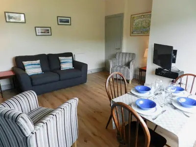 a living room with a table and chairs and a couch at Sunnyside Cottage in Lamlash