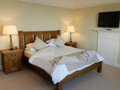 a bedroom with a bed with a tv on the wall at St Brides in Lamlash