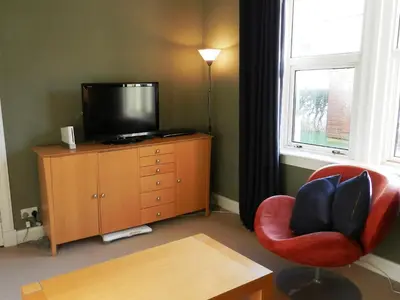 a living room with a television and a red chair at St Brides in Lamlash