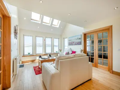 a living room with a white couch and windows at Sky View in Ardmaleish