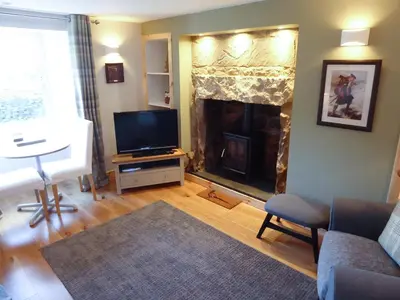 a living room with a television and a fireplace at Crosskeys Cottage in Shandon