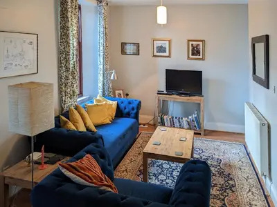 a living room with a blue couch and a table at Brough Hall in Paisley