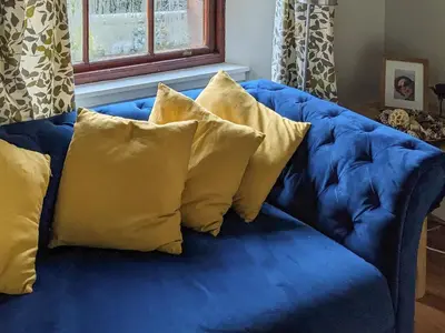 a blue couch with four yellow pillows on it at Brough Hall in Paisley