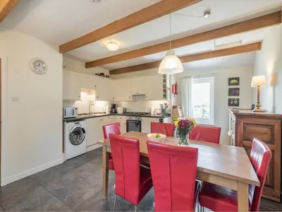 a kitchen and dining room with a wooden table and red chairs at Strathmaddie Farm Cottage in Palnure