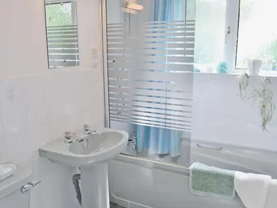 a white bathroom with a sink and a bath tub at Squirrel Cottage in Palnure