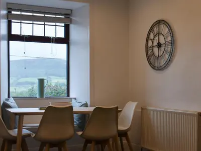 a dining room with a table and chairs and a clock at Park House in Blackwaterfoot