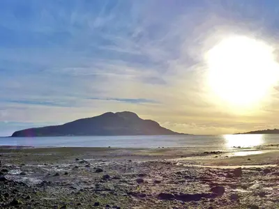 a view of a beach with a mountain in the background at Redhurst Cottage in Lamlash