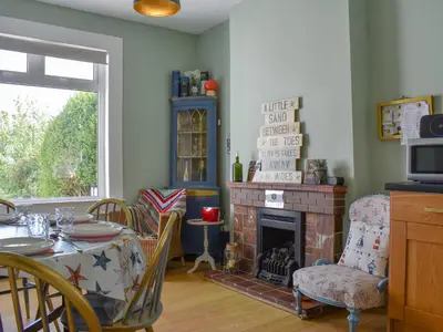 a living room with a table and a fireplace at Redhurst Cottage in Lamlash