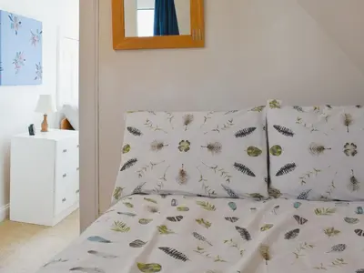 a bed in a room with a pillow and a mirror at Redhurst Cottage in Lamlash