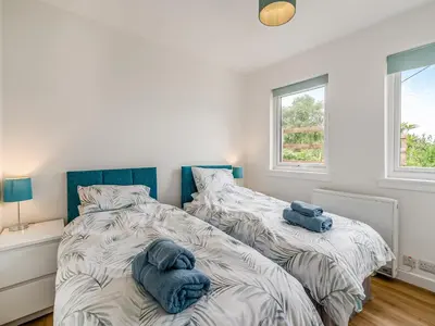 two beds in a bedroom with two blue towels at Sea Breeze Cottage in Lochranza