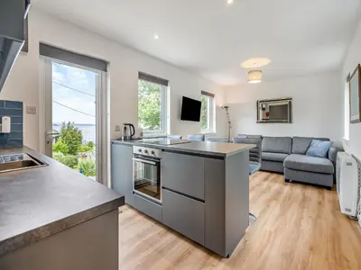 a kitchen and living room with a stove and a couch at Sea Breeze Cottage in Lochranza