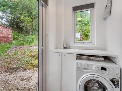 a washing machine in a room with a window at Sea Breeze Cottage in Lochranza