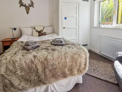 a bedroom with a large bed with a brown blanket at An Cala in Brodick