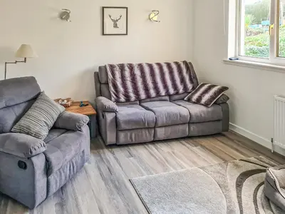 a living room with a couch and a chair at An Cala in Brodick