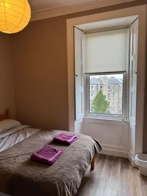 a bedroom with a window with purple towels on a bed at Central Room In Historic Tenement Shared Apartment Near Old Town in Edinburgh