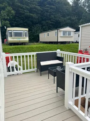 a deck with a table and chairs and a trailer at 23 Chestnut Grove in Kirkcolm