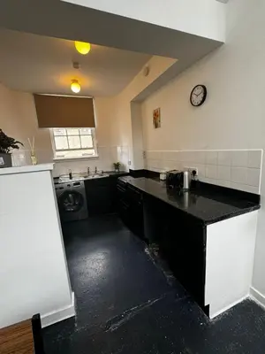 a kitchen with a black counter and a clock on the wall at Victoria Street View Flat in Edinburgh EB10 in Edinburgh