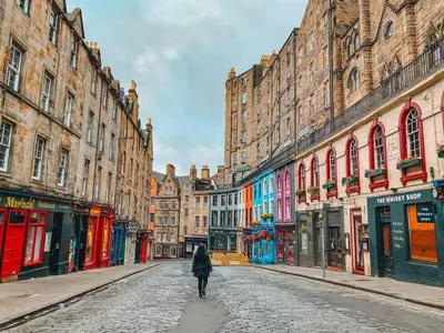 a person walking down a cobblestone street in a city at Victoria Street View Flat in Edinburgh EB10 in Edinburgh
