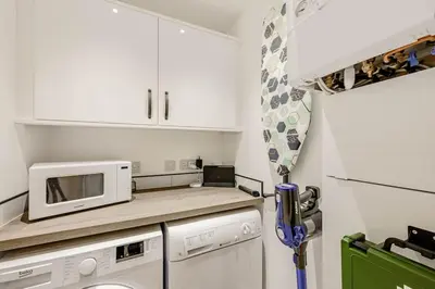 a small kitchen with white cabinets and a microwave at Cowden Coorie in Fife