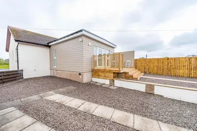 a house with a deck and a fence at Cowden Coorie in Fife
