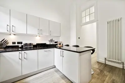 a kitchen with white cabinets and black counter tops at Timeless 5 bed Duplex Flat in Glasgow