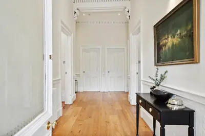 a hallway with a table and a painting on the wall at Timeless 5 bed Duplex Flat in Glasgow