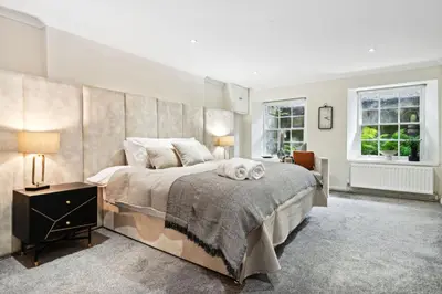 a bedroom with a large bed with a dog laying on it at Timeless 5 bed Duplex Flat in Glasgow