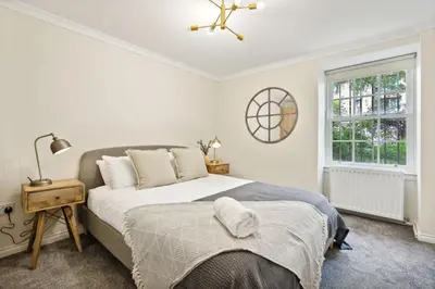 a white bedroom with a bed and a window at Timeless 5 bed Duplex Flat in Glasgow