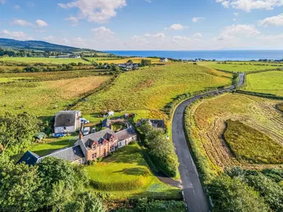 an aerial view of a house in a field with a road at Burncliff in Blackwaterfoot