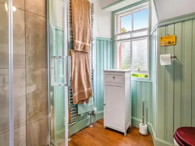 a bathroom with a shower and a toilet and a window at Burncliff in Blackwaterfoot