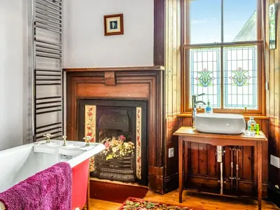 a bathroom with a fireplace and a tub and a sink at Burncliff in Blackwaterfoot
