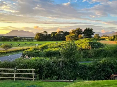 a field with a fence and animals in the distance at Burncliff in Blackwaterfoot