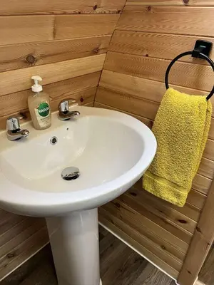 a bathroom with a white sink and a yellow towel at Penny gown farm pod in Campbeltown