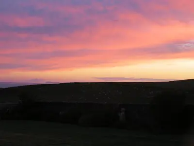 a person standing in a field at sunset at Hazel's Cottage in Campbeltown