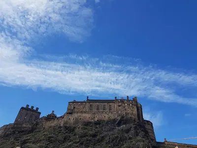 a castle on top of a mountain under a cloudy sky at 223 Websters land - stunning castle view in Edinburgh